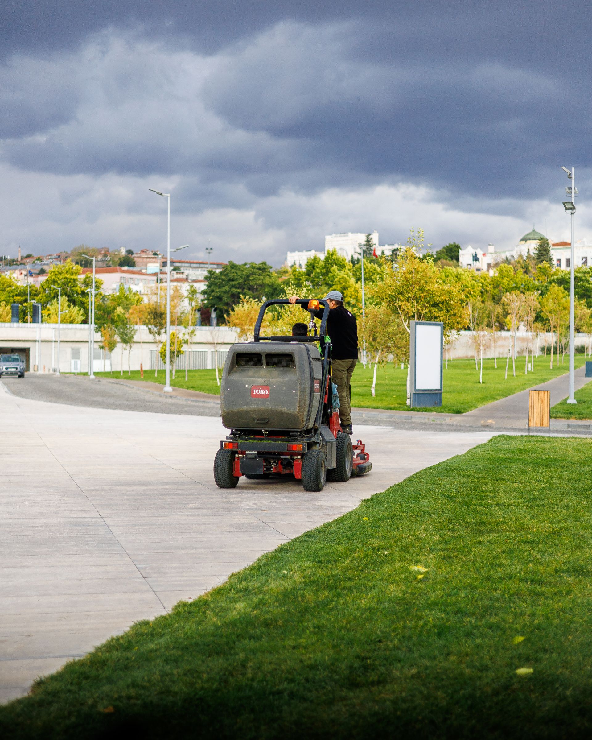 Worker operating a ride-on mower on a large lawn